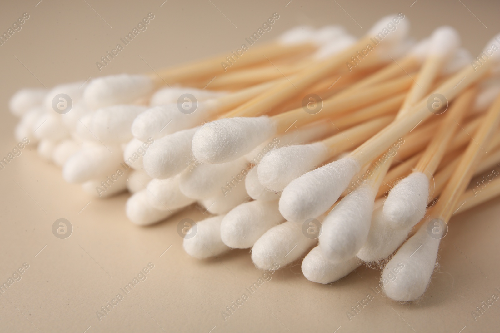 Photo of Many clean cotton buds on beige background, closeup