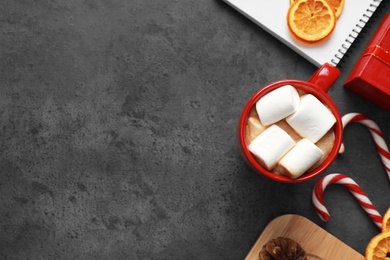 Flat lay composition with cup of tasty cocoa and sweets on dark grey table, space for text. Cozy winter