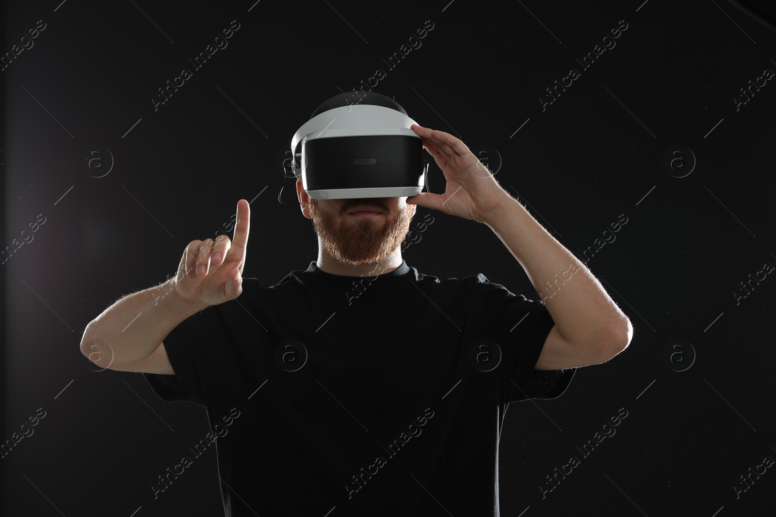 Photo of Man using virtual reality headset on black background