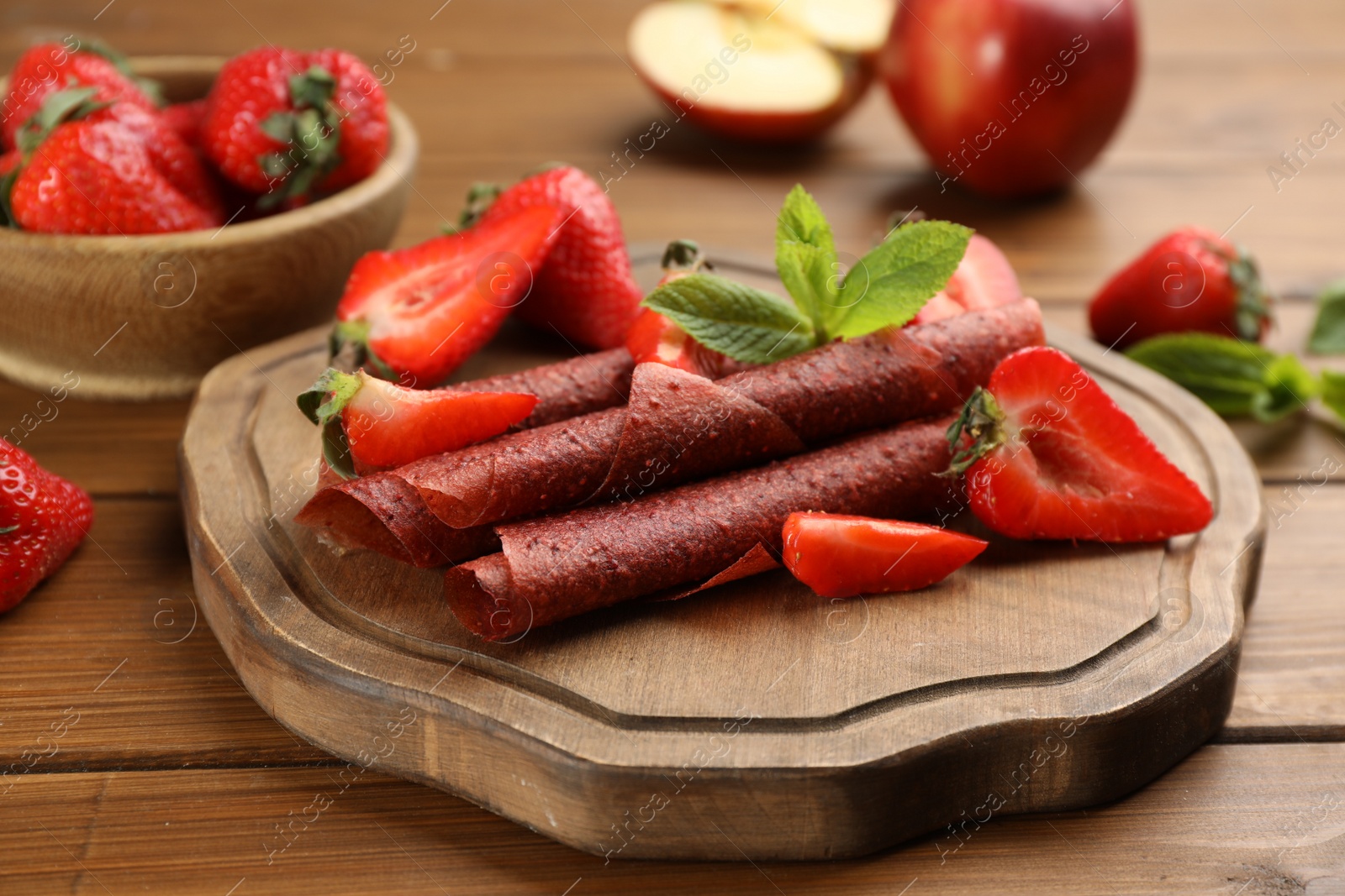 Photo of Composition with delicious fruit leather rolls on wooden table