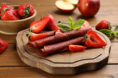 Composition with delicious fruit leather rolls on wooden table