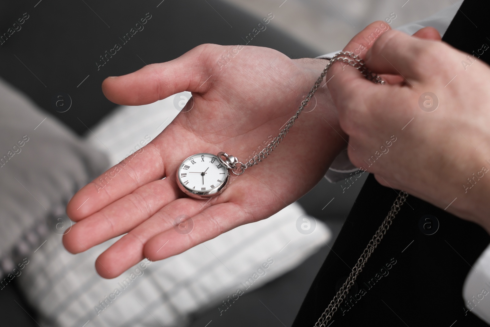 Photo of Man holding chain with elegant pocket watch on blurred background, closeup