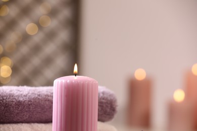 Spa composition. Burning candle and towels against blurred background, space for text