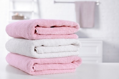 Photo of Stack of fresh towels on table in bathroom. Space for text