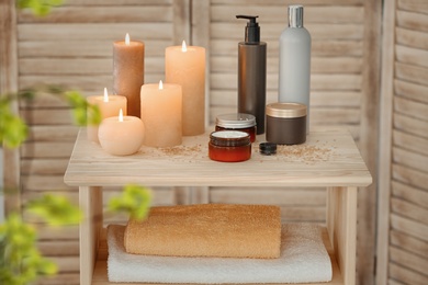 Photo of Body care cosmetics and burning candles on table