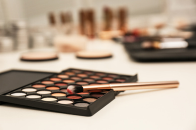 Photo of Brush and eyeshadow palette on professional makeup artists workplace, closeup