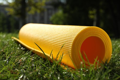 Photo of Bright exercise mat on fresh green grass outdoors, closeup