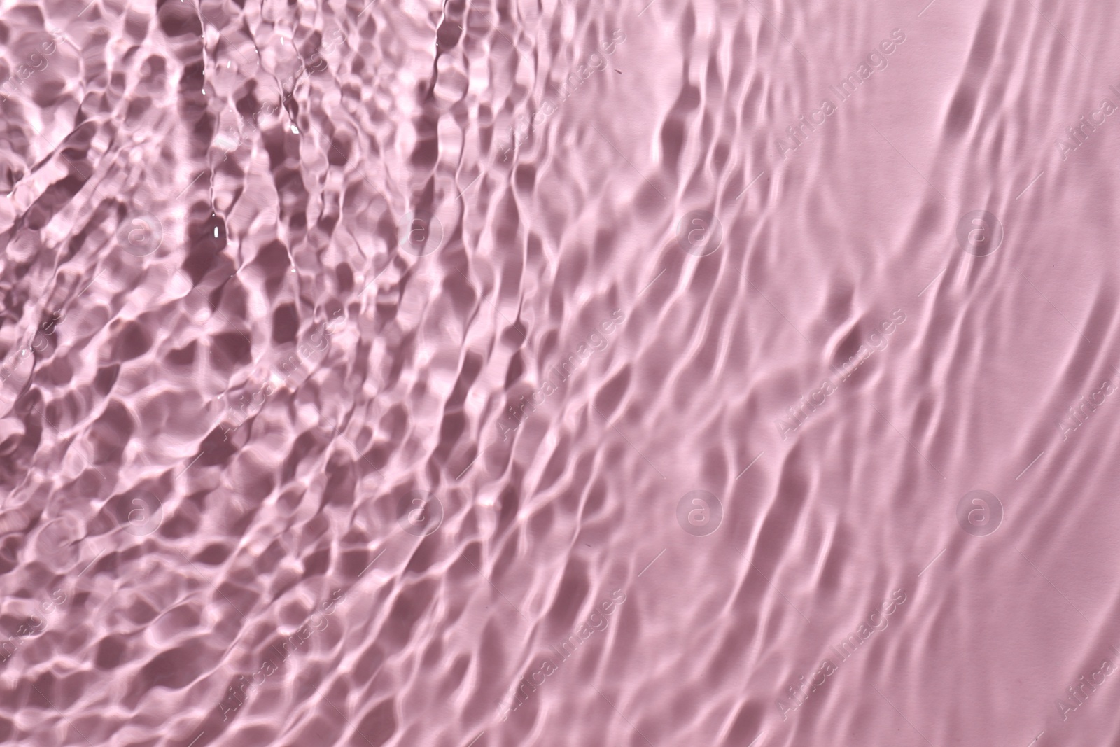 Photo of Rippled surface of clear water on pink background, top view