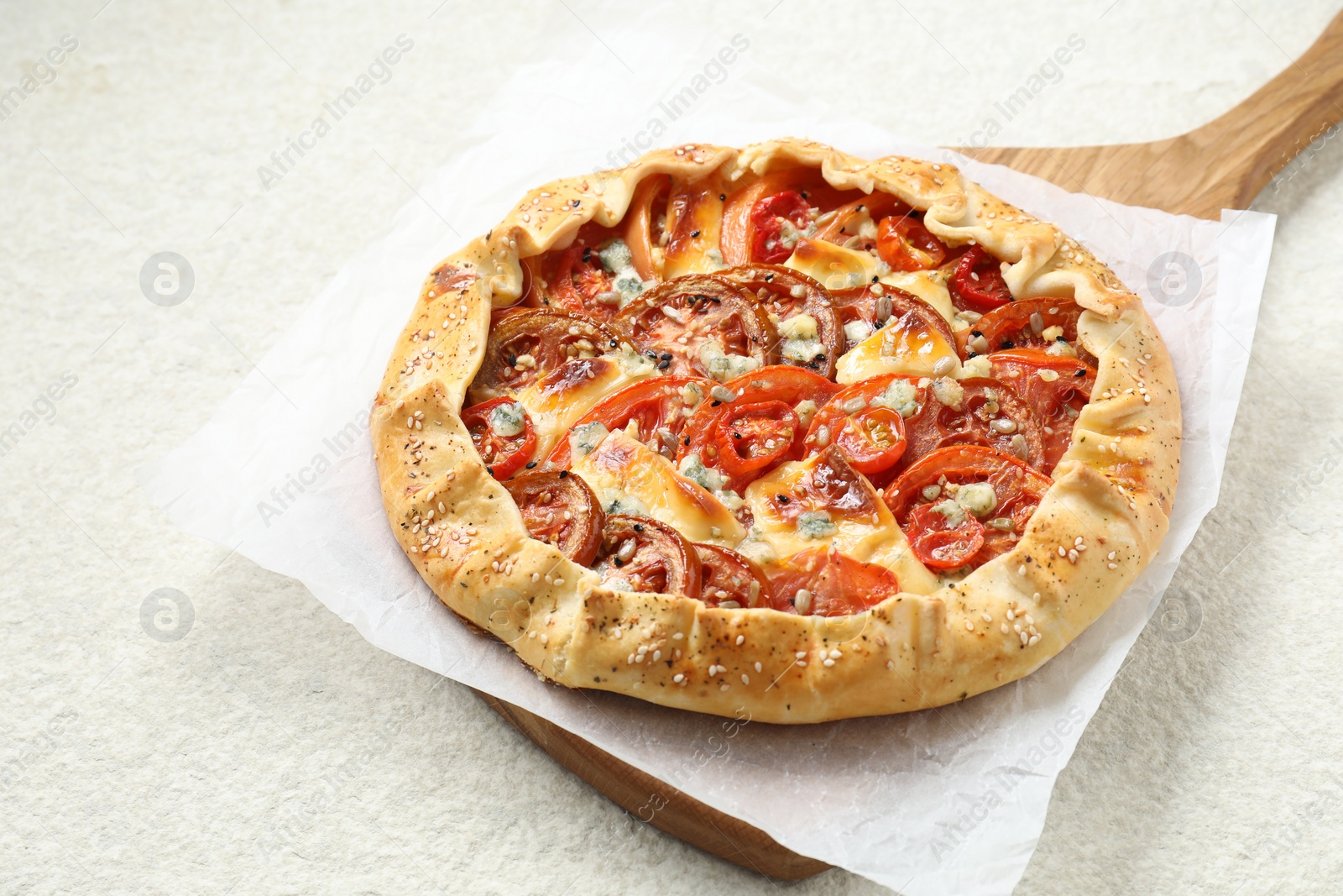 Photo of Tasty galette with tomato and cheese (Caprese galette) on light textured table, closeup