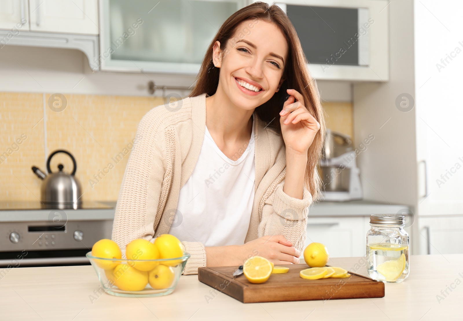 Photo of Young woman making lemon water in kitchen