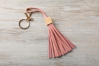 Photo of Pink leather keychain on light wooden background, top view