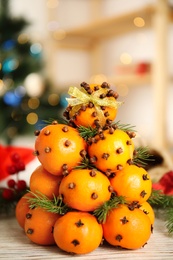 Pomander balls made of tangerines with cloves and fir branches on white wooden table