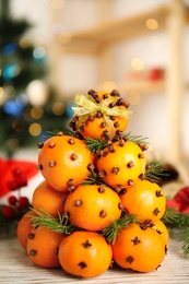 Photo of Pomander balls made of tangerines with cloves and fir branches on white wooden table