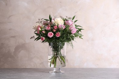 Photo of Beautiful bouquet with roses on table against grey background