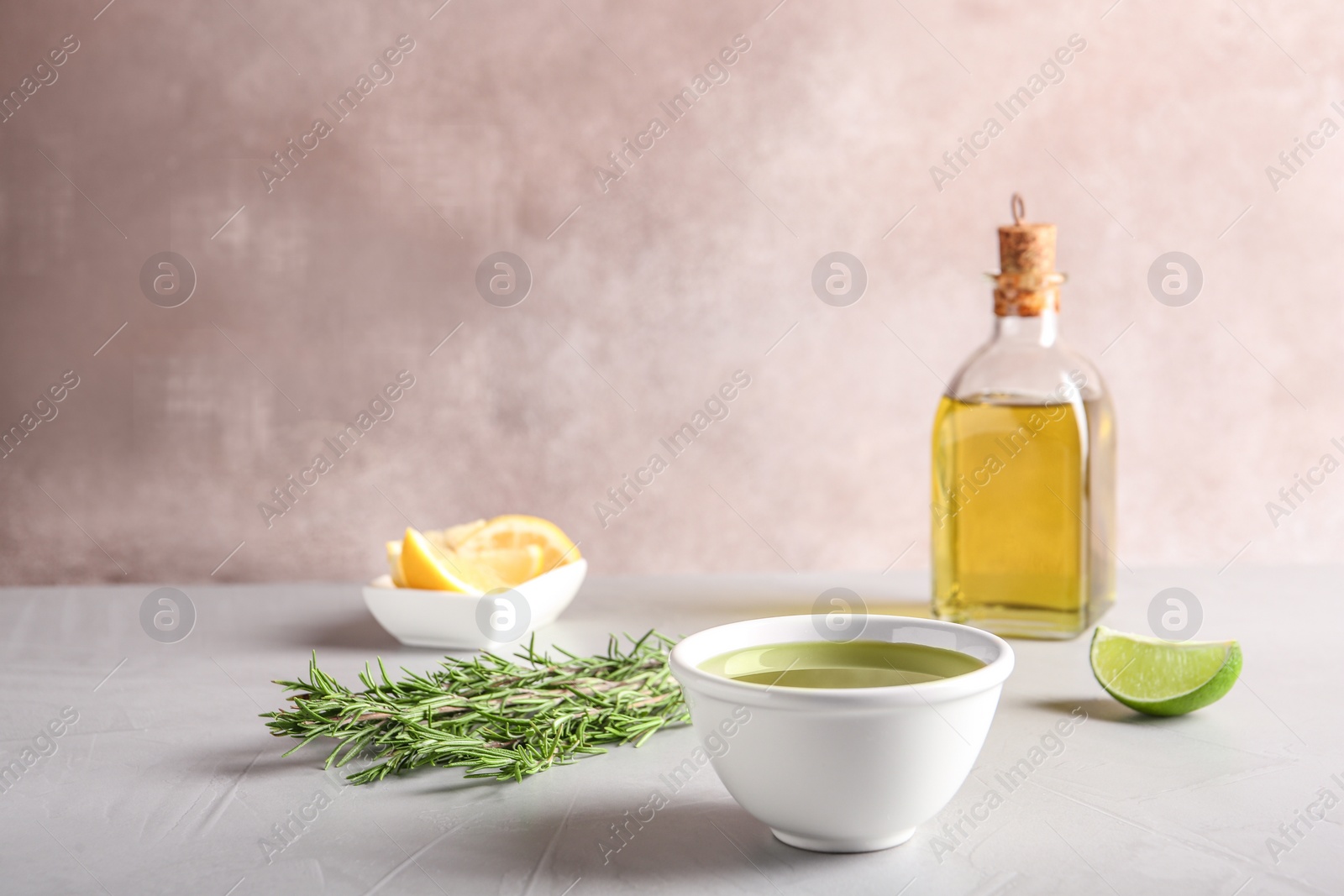 Photo of Bowl with fresh rosemary oil on table