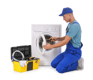 Plumber repairing washing machine on white background