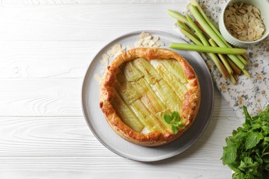 Photo of Freshly baked rhubarb pie and stalks on white wooden table, flat lay. Space for text