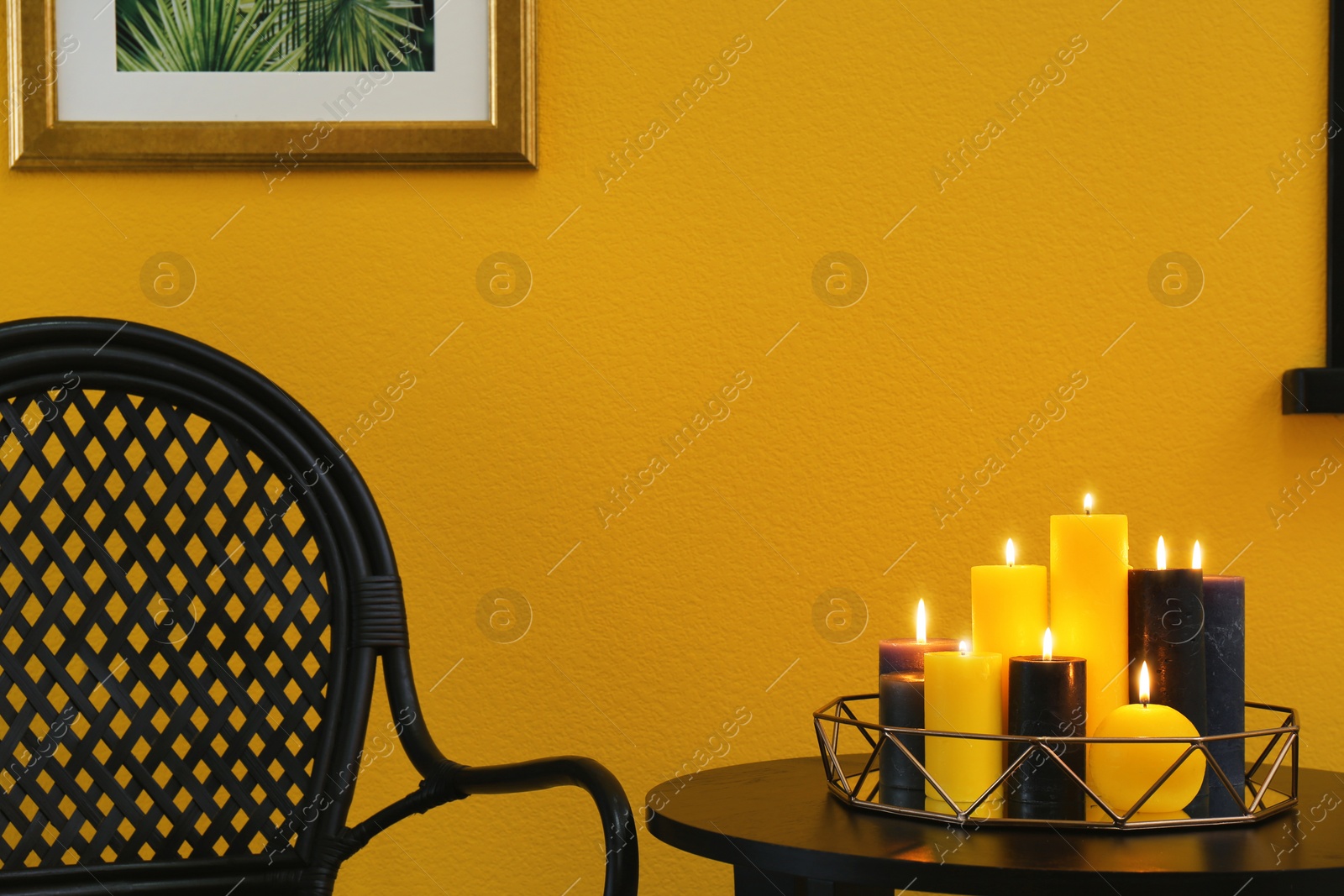 Photo of Burning candles on table near color wall in room. Space for text