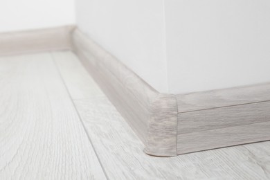 Photo of Wooden plinth with connector on laminated floor near white wall indoors, closeup