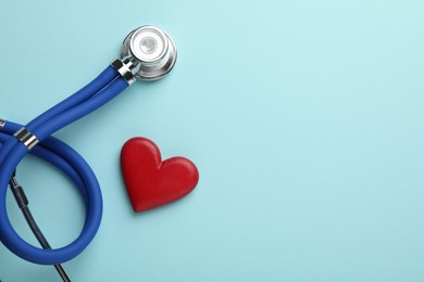 Stethoscope and red heart on light blue background, top view. Space for text