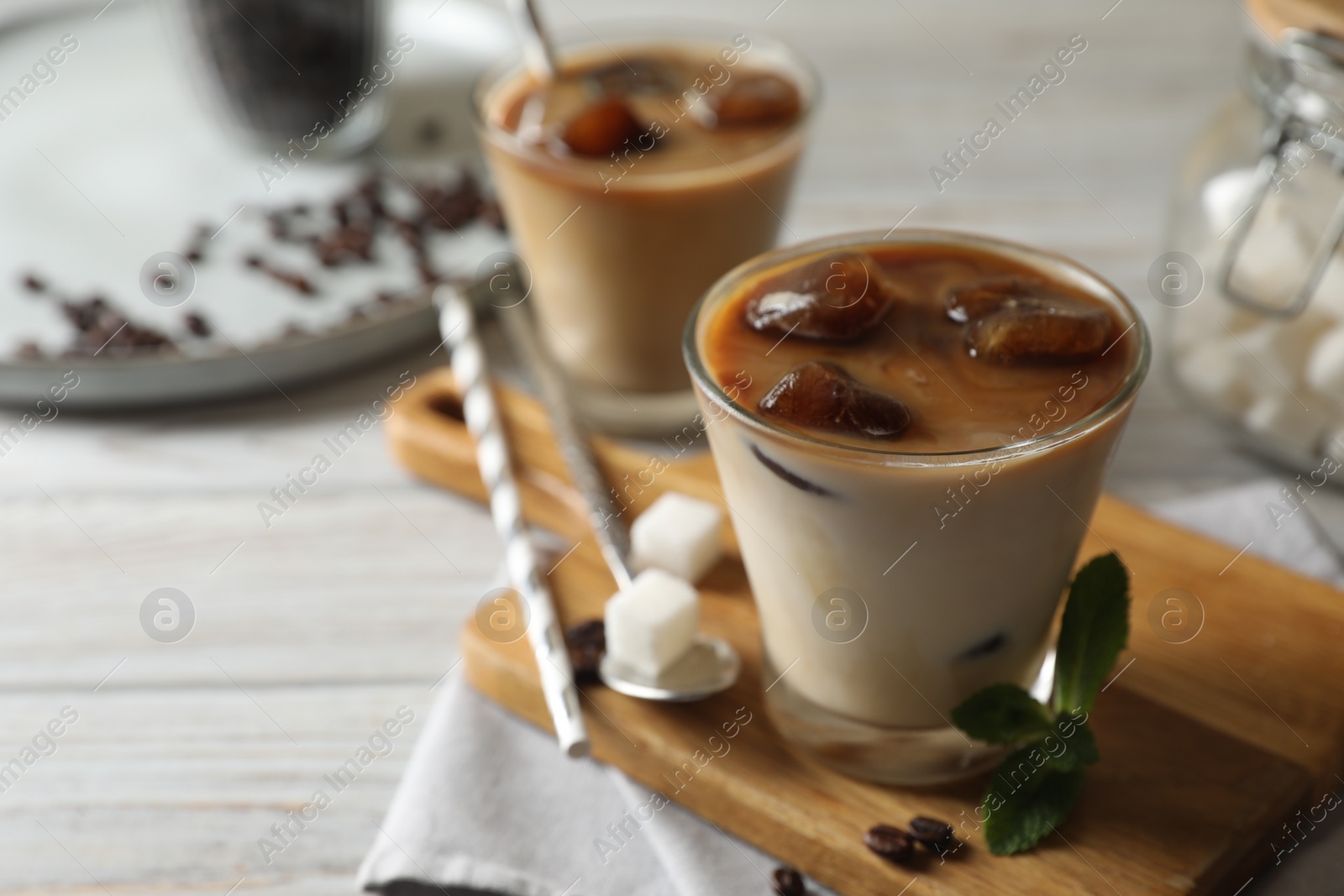 Photo of Delicious iced coffee on white wooden table, closeup. Space for text