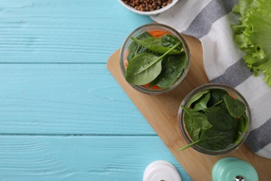 Flat lay composition with jars of healthy food on light blue wooden background, space for text