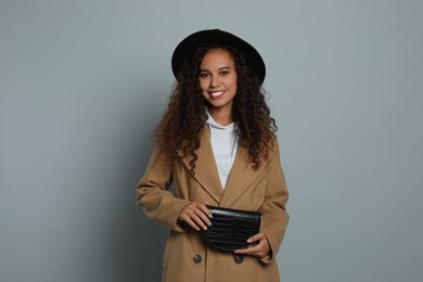 Photo of Beautiful African American woman with stylish waist bag on grey background