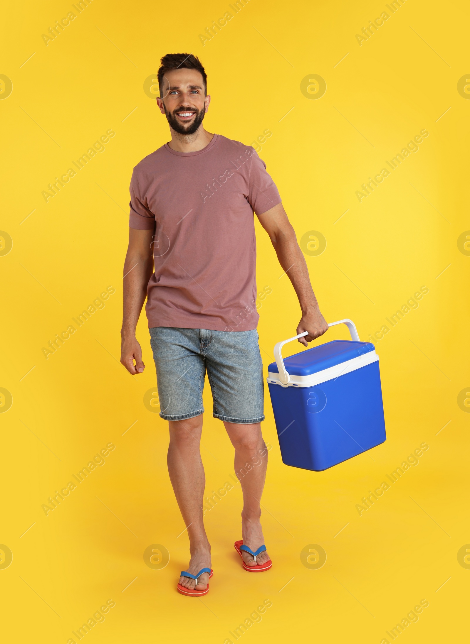 Photo of Happy man with cool box on yellow background