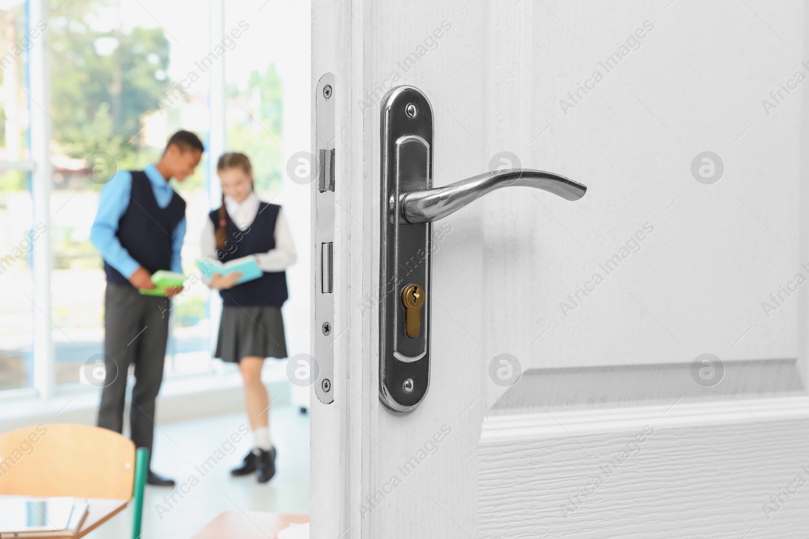 Image of Wooden door open into modern classroom with students