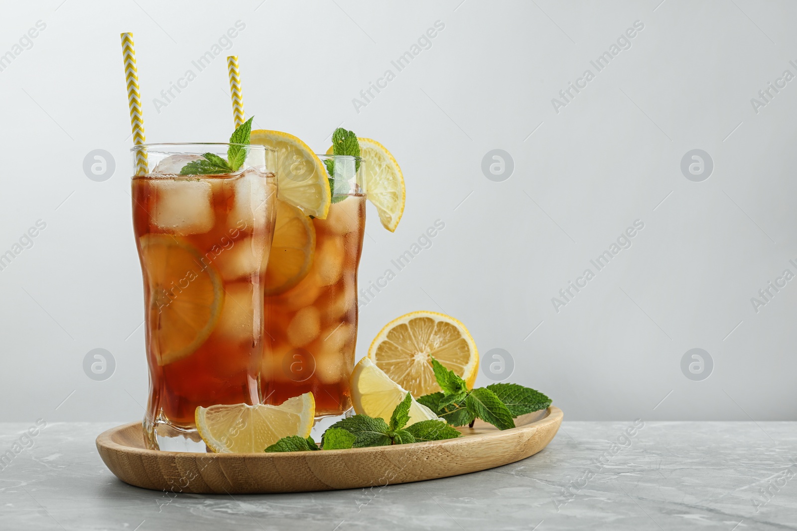 Photo of Glasses of delicious iced tea on table against light background.