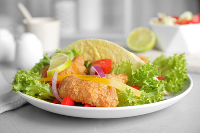 Photo of Delicious fish tacos served on light  grey table, closeup