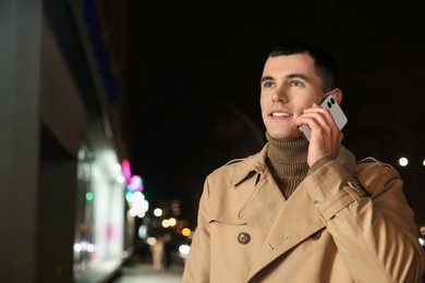 Man talking by smartphone on night city street, space for text