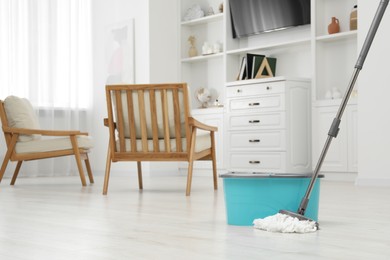 Photo of Mop and bucket on white parquet in room, space for text. Cleaning floor