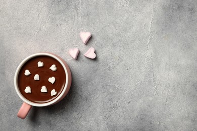 Cup of hot chocolate with heart shaped marshmallows on light grey table, flat lay. Space for text