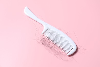 Photo of Comb with lost hair on pink background