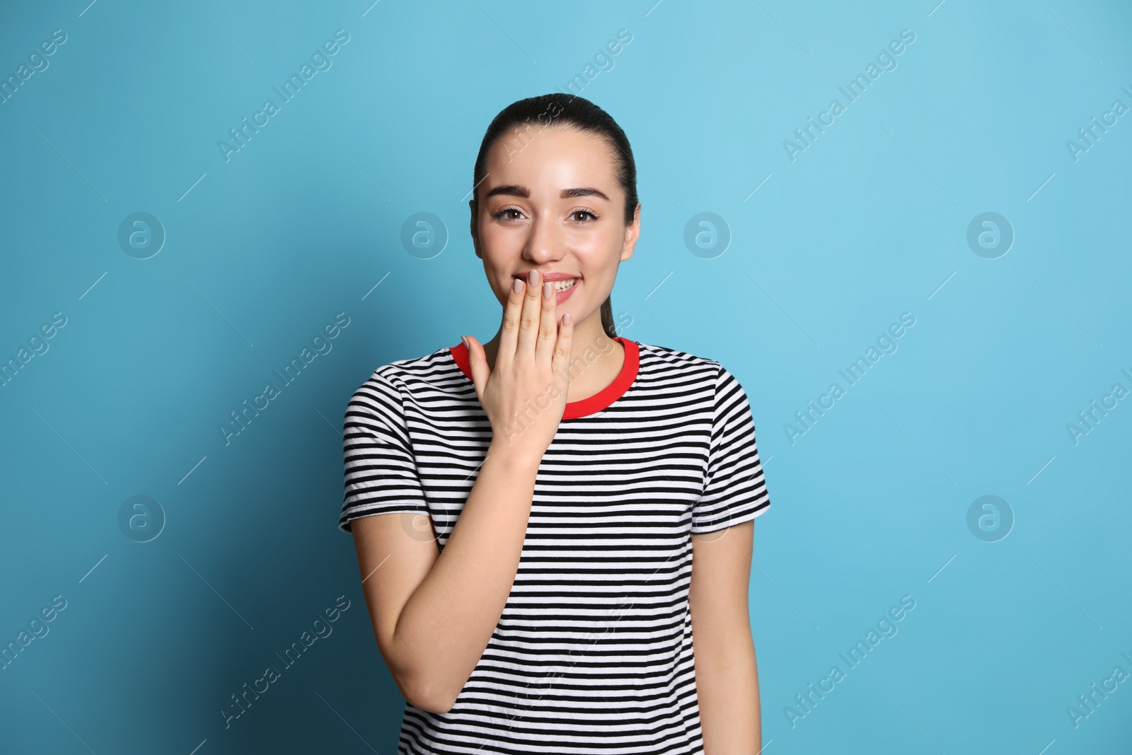 Photo of Beautiful young woman laughing on light blue background. Funny joke