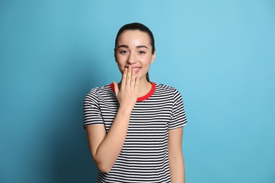 Photo of Beautiful young woman laughing on light blue background. Funny joke