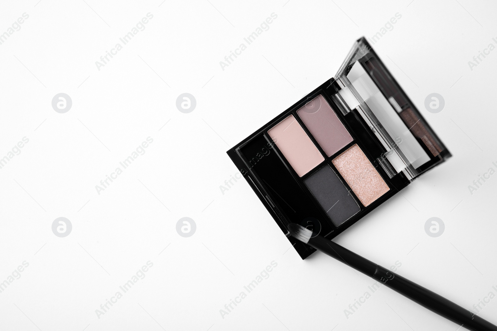 Photo of Eye shadow palette and professional makeup brush on white background, top view. Space for text