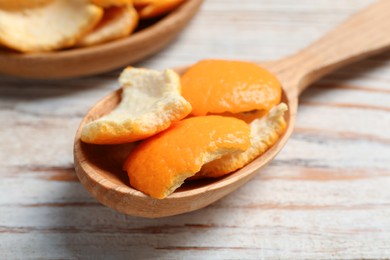 Photo of Orange peels preparing for drying and spoon on wooden table, closeup