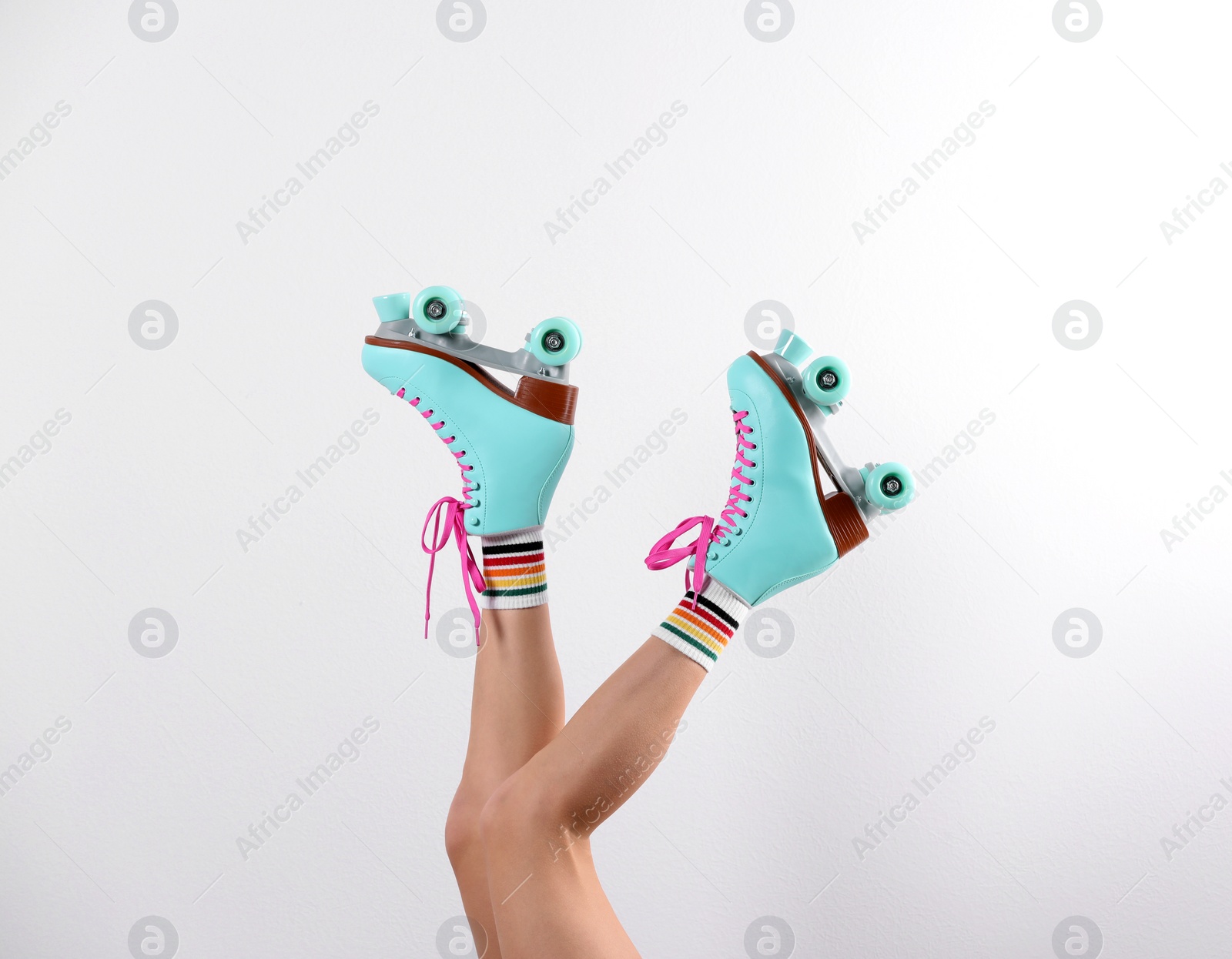 Photo of Young woman with retro roller skates on white background, closeup