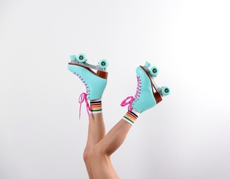 Photo of Young woman with retro roller skates on white background, closeup