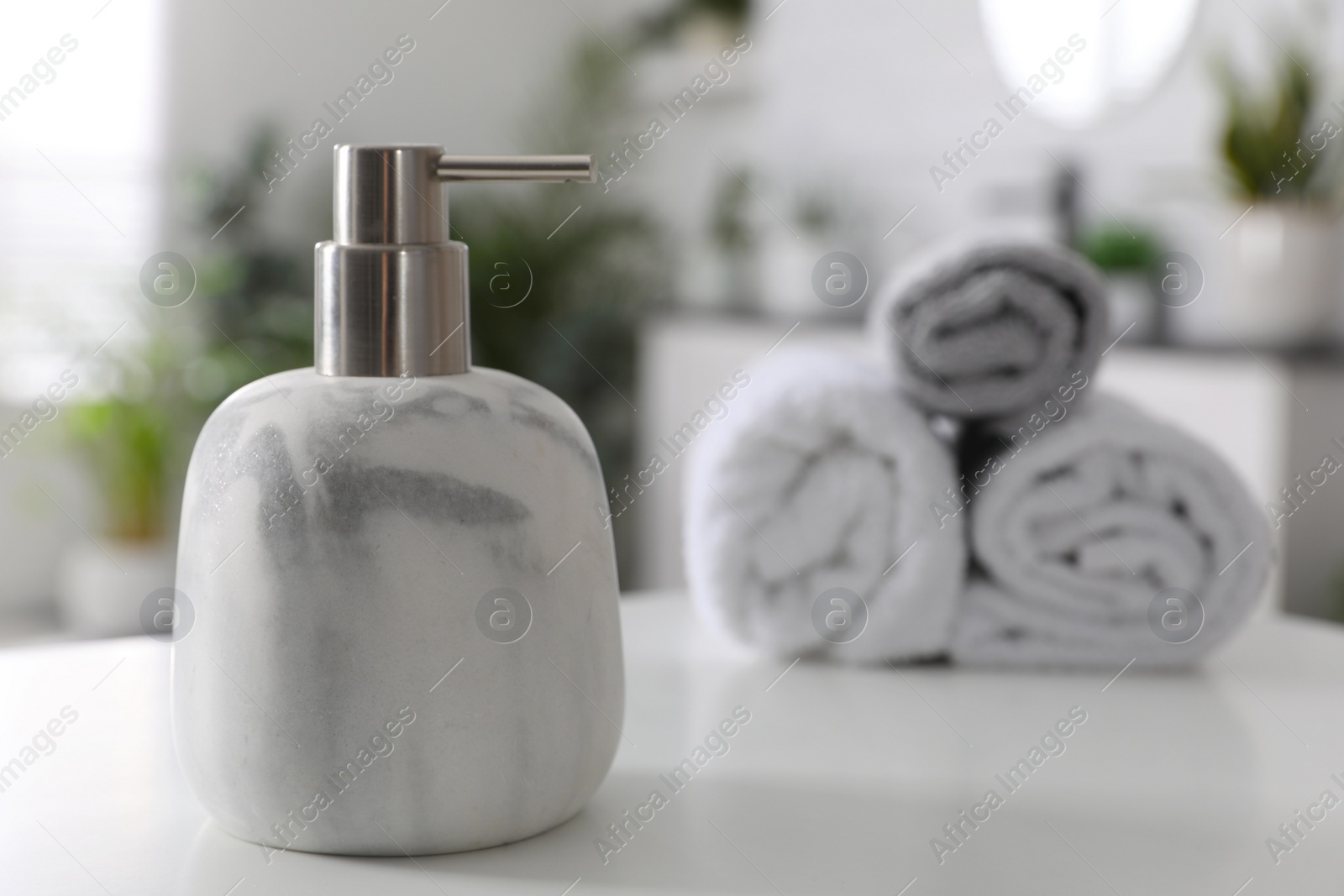 Photo of Dispenser with liquid soap near towels on white table in bathroom, space for text