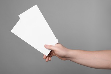 Woman holding flyers on grey background, closeup. Mockup for design