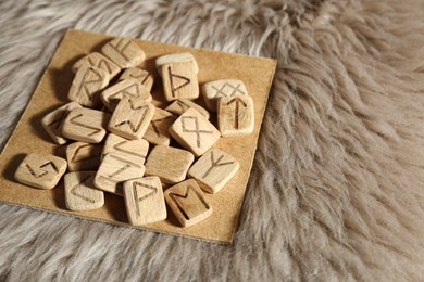 Photo of Many wooden runes on fur, closeup. Space for text