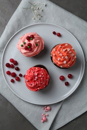 Photo of Delicious cupcakes with pink cream and berries on grey table, top view
