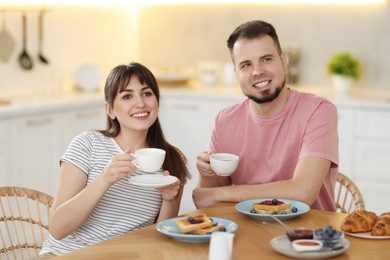 Happy couple having tasty breakfast at home