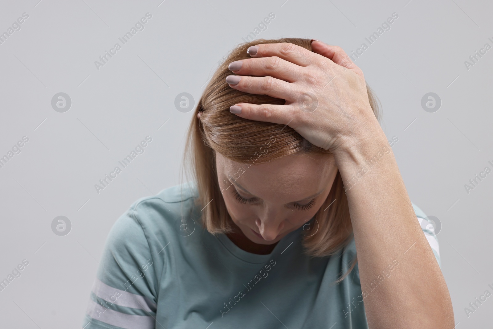 Photo of Sad woman in light blue t-shirt on grey background