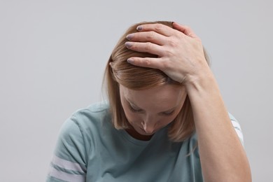 Sad woman in light blue t-shirt on grey background