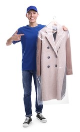 Photo of Dry-cleaning delivery. Happy courier holding coat in plastic bag on white background