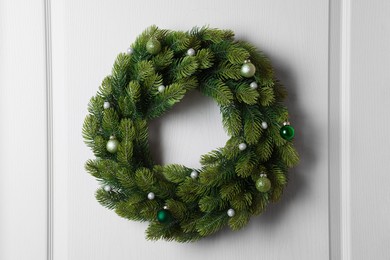 Beautiful Christmas wreath with festive decor hanging on white door